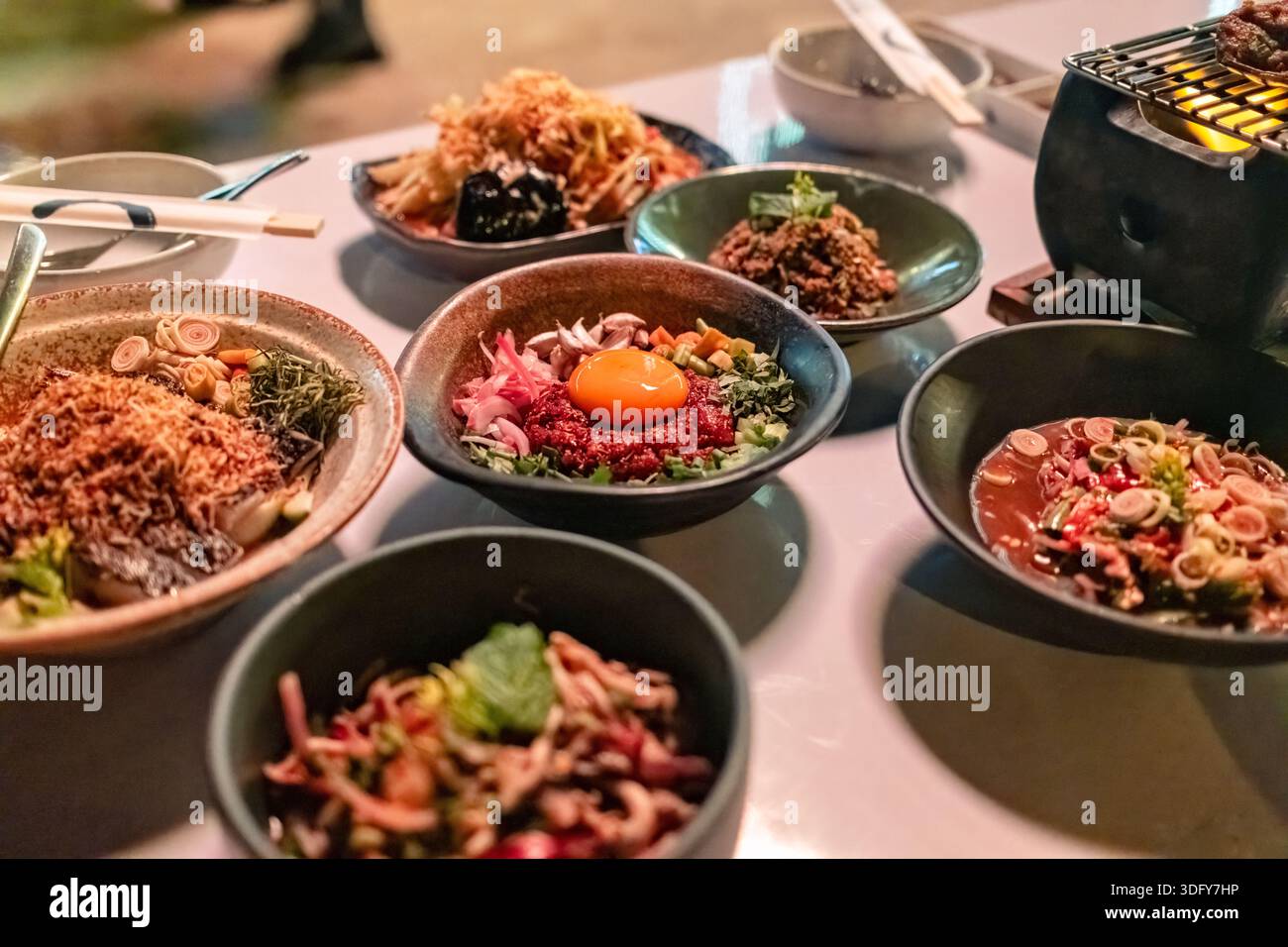 Asiatische isaanische Fusion-Küche mit verschiedenen seltenen Schweinefleisch mit Kräutern, scharfem Salat und Herd auf dem Tisch im Thai Food Restaurant Stockfoto