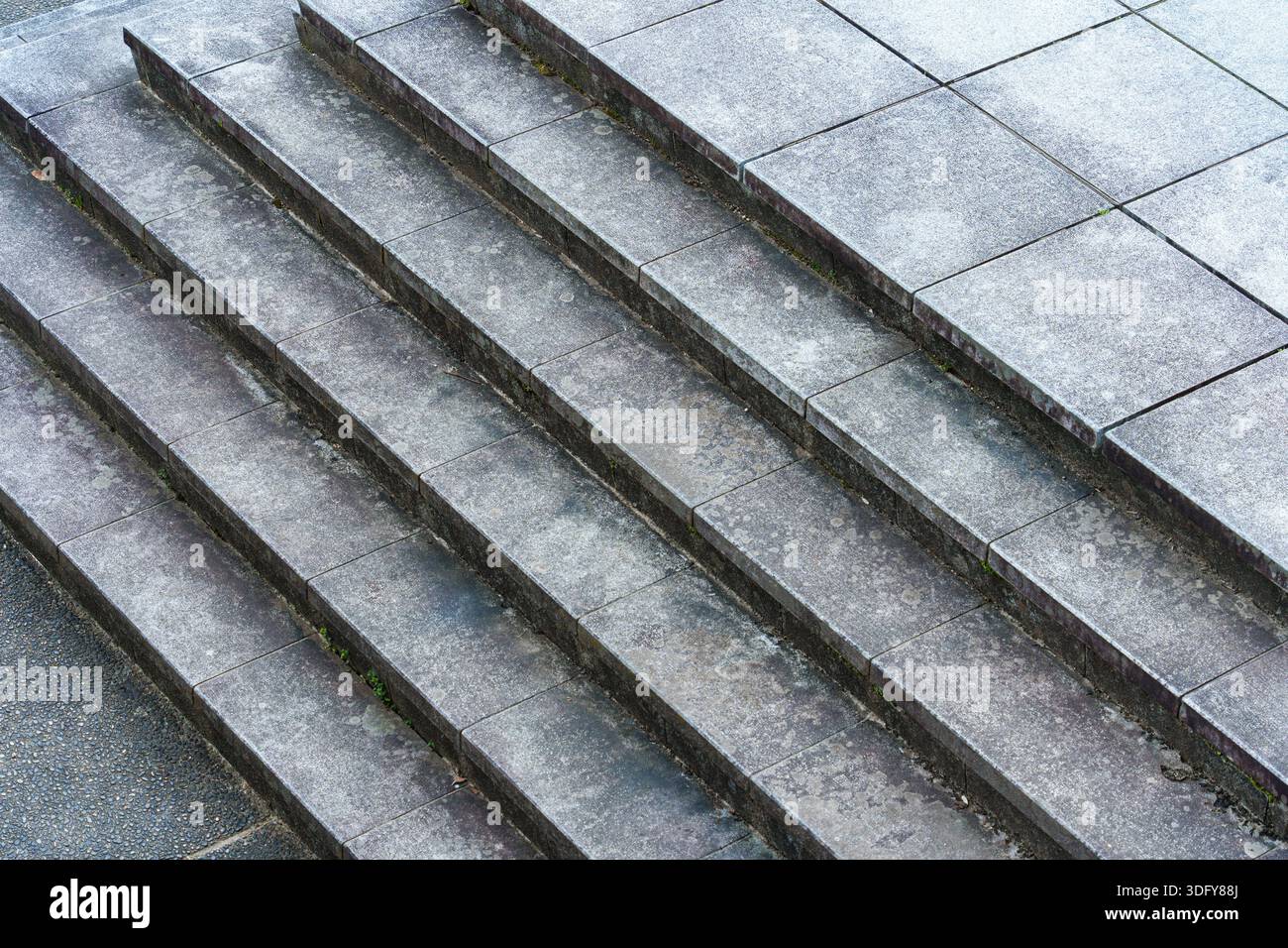 Geometrische Betonplattform mit mehrschichtigen Steinstufen, die eine symmetrische architektonische Struktur im öffentlichen Raum im Freien bilden Stockfoto