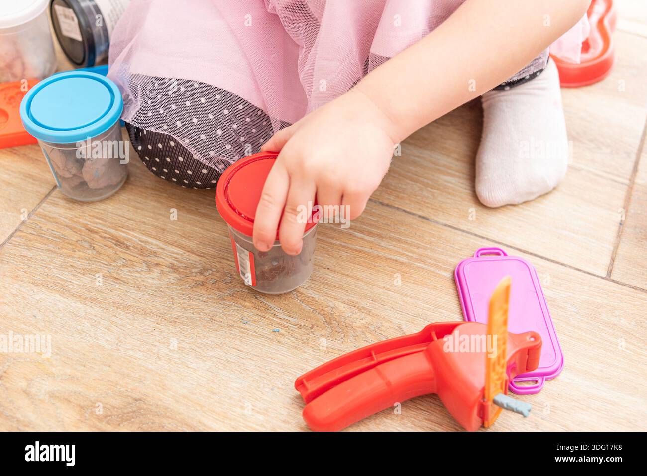 Niedliches Kleinkind, das auf dem Boden sitzt und Plastilin spielt, Kinder Hobby-Kreativität Stockfoto