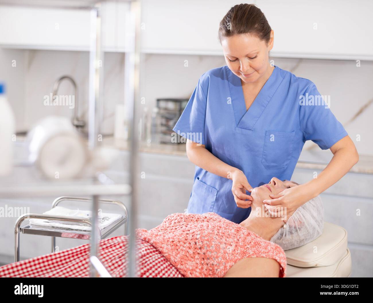 Erfahrener Arzt, der eine Gesichtsmassage an einen Reifen Patienten durchführt Stockfoto