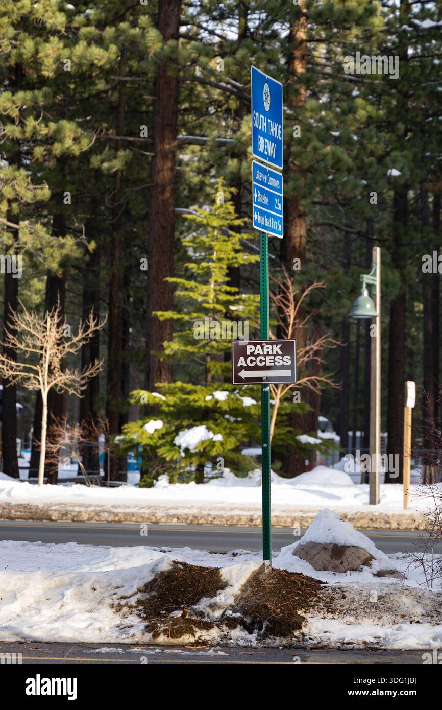 Ein Parkplatzschild zeigt Informationen zum Parkplatzzugang in South Lake Tahoe an. Schnee bedeckt den Boden und Bäume umgeben den Ort. Es scheint Winter zu sein Stockfoto
