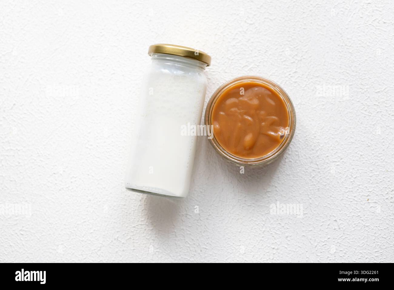 Nahaufnahme einer cremigen Karamellmilchmarmelade Dulce de leche in einem Glas mit frischer Milch Stockfoto