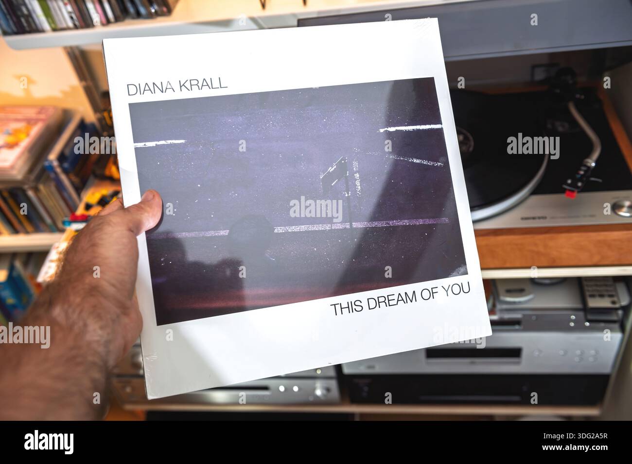 Paris, Frankreich - 9. September 2025: A Hand präsentiert die Diana Krall This Dream of You audiophile LP in ihrer Schrumpffolie, die über einem Plattenspieler und Regalen gehalten wird Stockfoto