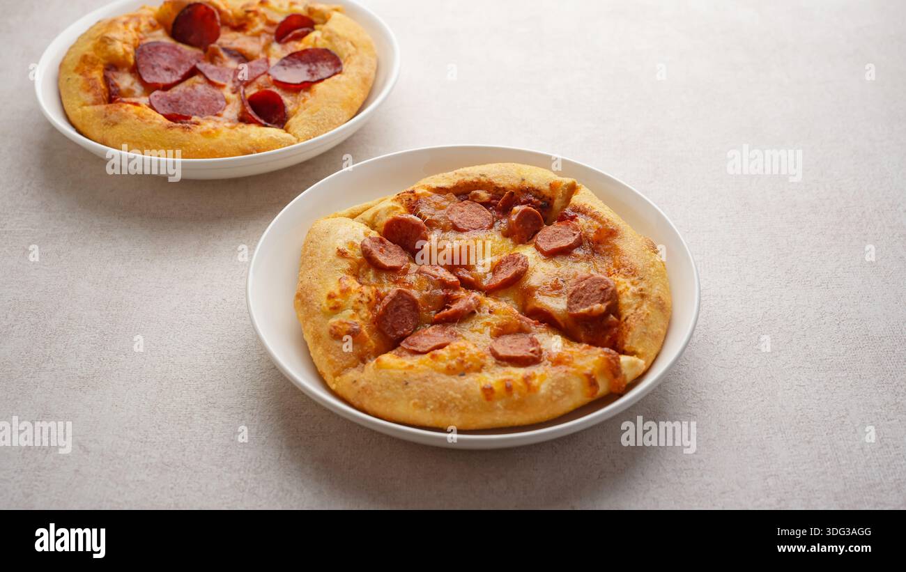 Kleine Pizza mit Wurst und Käse auf Teller Stockfoto
