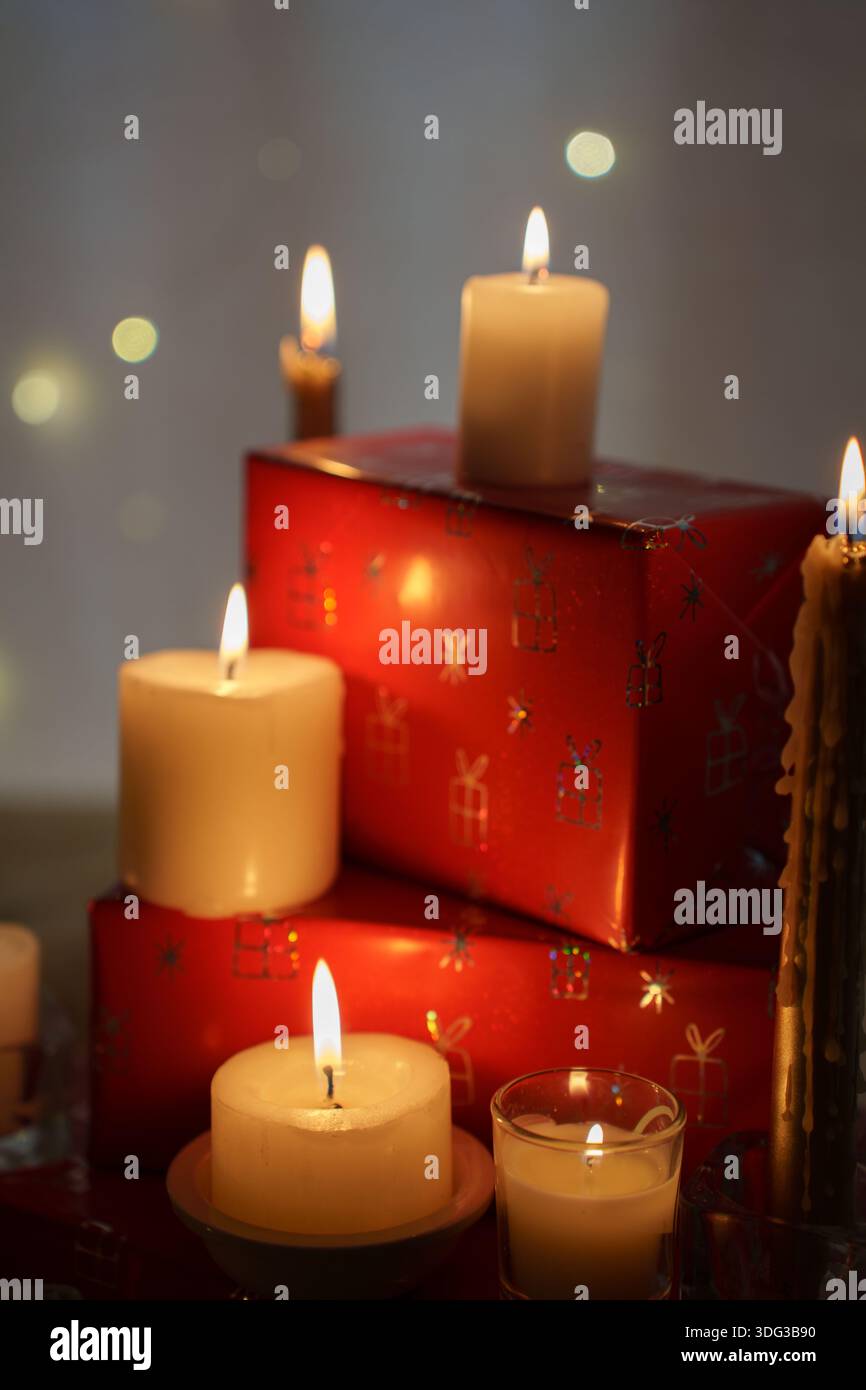 Warmes Urlaubsambiente mit leuchtenden Kerzen und festlicher Einrichtung in sanftem Licht, roten Geschenkboxen und sanften Kerzenflammen, die eine gemütliche, ruhige Atmosphäre schaffen Stockfoto
