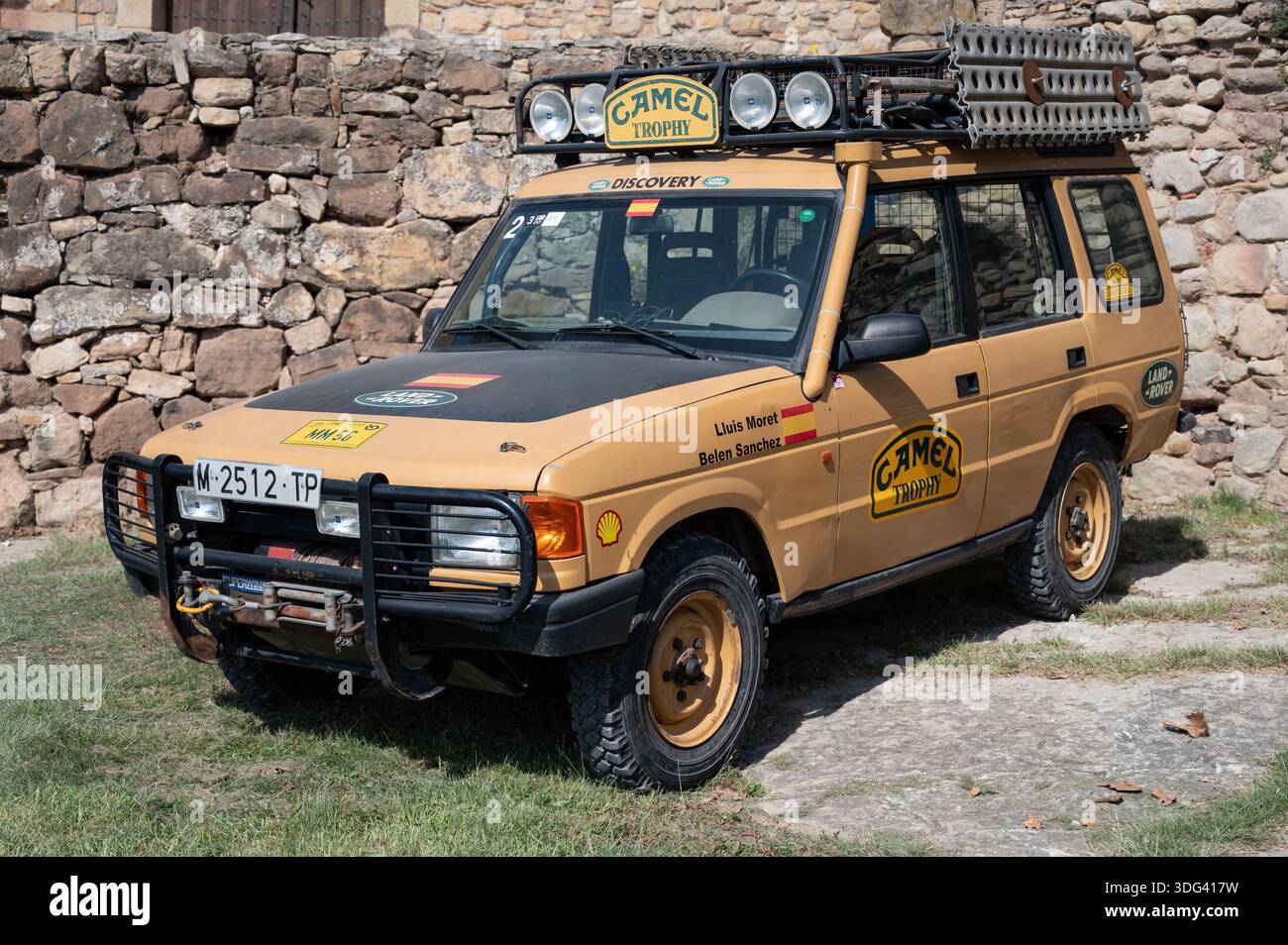 Detaillierte Ansicht eines klassischen Camel Trophy Land Rover Discovery Series I Expeditionsfahrzeugs mit voller Geländeausrüstung, das neben einem rustikalen Steinhaus im geparkt wird Stockfoto