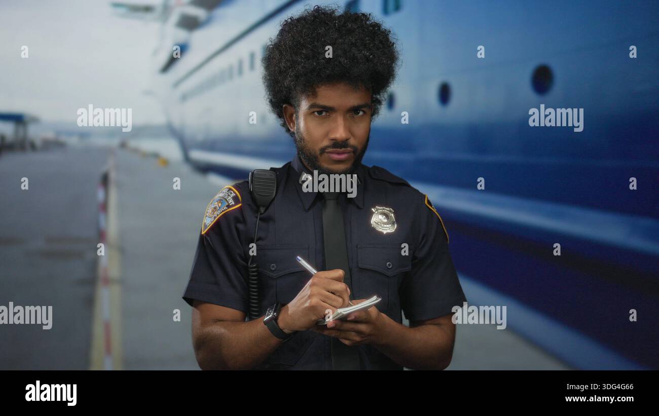 afroamerikaner in Polizeiuniform, der draußen an einem Seehafen Notizen schreibt, mit einem großen Boot im Hintergrund, was ein Gefühl von Pflicht und Autotyp vermittelt Stockfoto