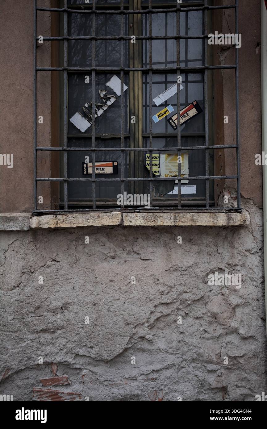Mantova, Italien - 19. FEBRUAR 2025 - Alte Werbeaufkleber an einem Fenster hinter einem Gitter Stockfoto