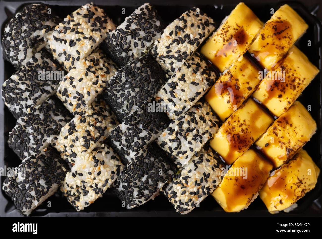 Eine detaillierte Aufnahme einer Reihe japanischer Sushi-Brötchen mit Sesam. Stockfoto