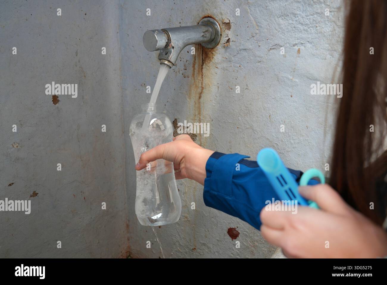 Nachfüllung der PET-Plastikflasche aus öffentlichem Wasserhahn in Bunol, Spanien. Kommunaler Trinkwasserhahn - nachhaltiger Tourismus. Stockfoto