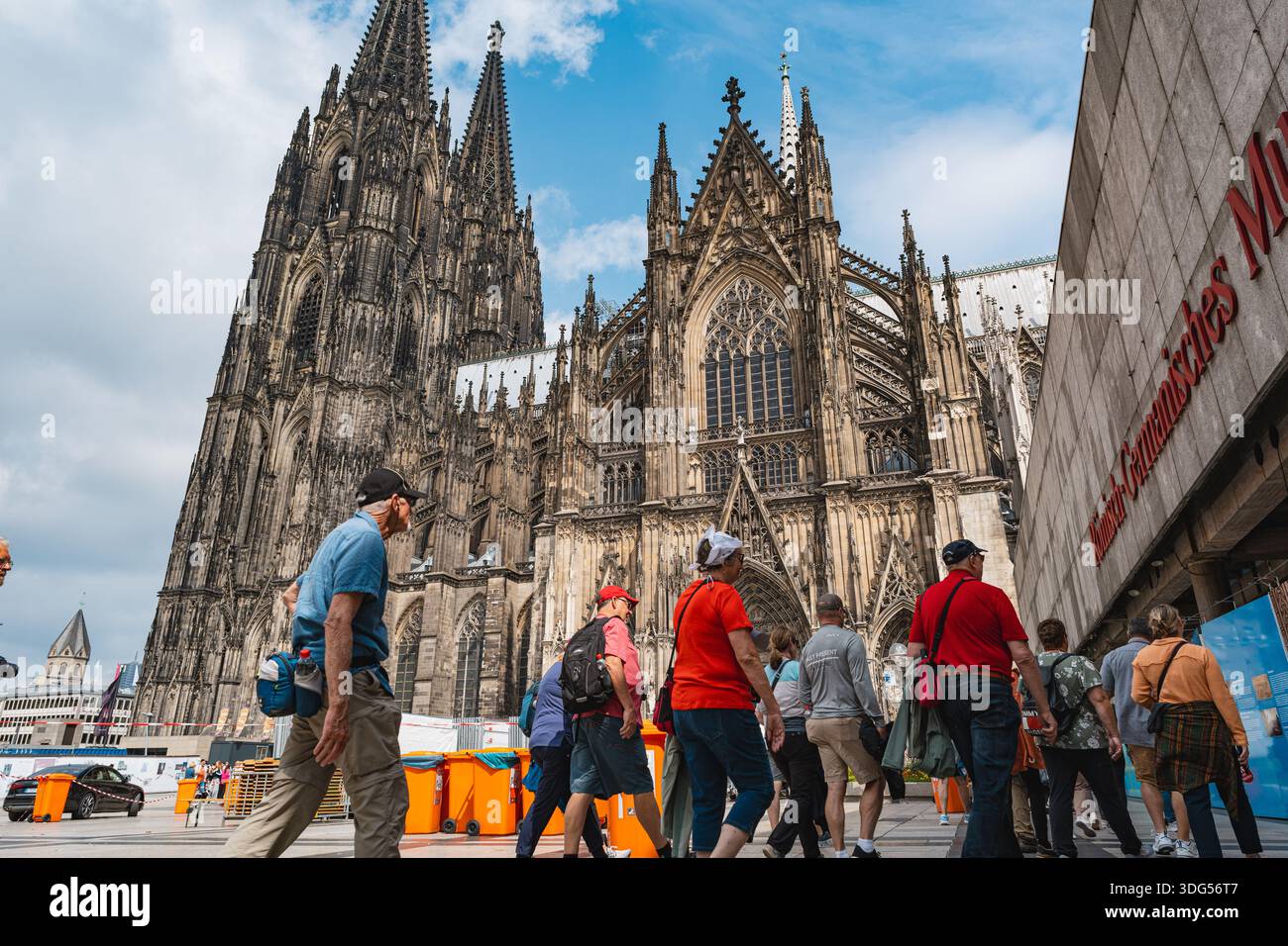 Touristen, die in der Nähe der majestätischen gotischen Kölner Domfassade spazieren Stockfoto