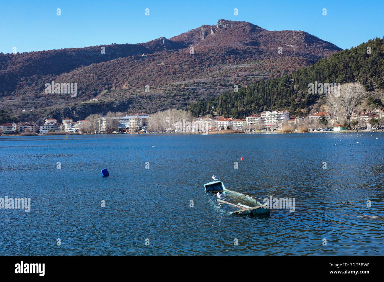 Ein teilweise versunkenes Boot ruht still auf dem ruhigen See von Kastoria, Griechenland Stockfoto