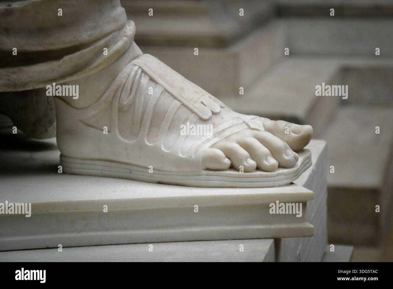 Nahaufnahme des Fußes der antiken Marmorstatue in Sandal – klassisches Skulpturendetail Stockfoto