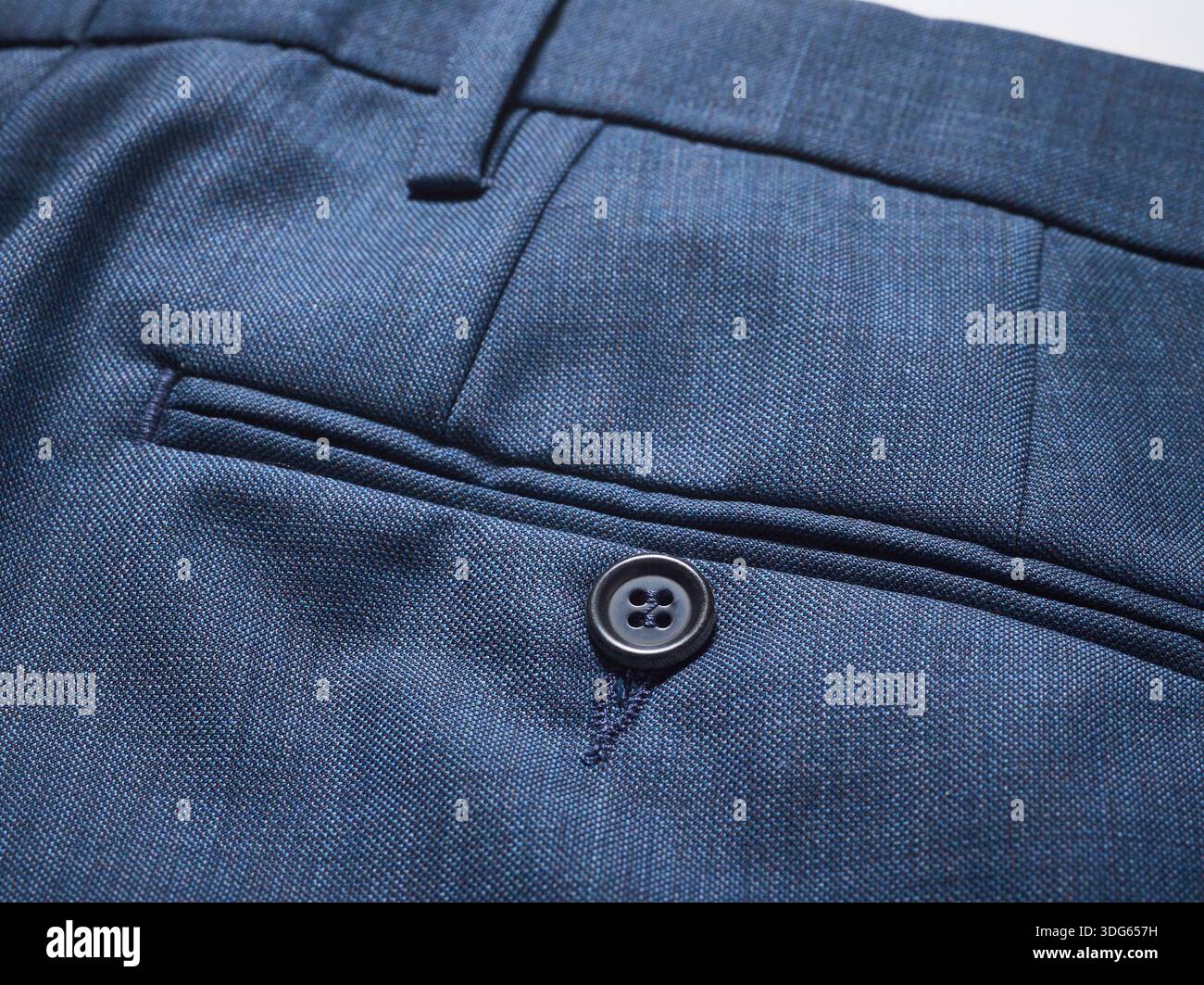Nahaufnahme einer eleganten blauen Hosentasche mit Knopfdetail und feiner Stoffstruktur. Stockfoto