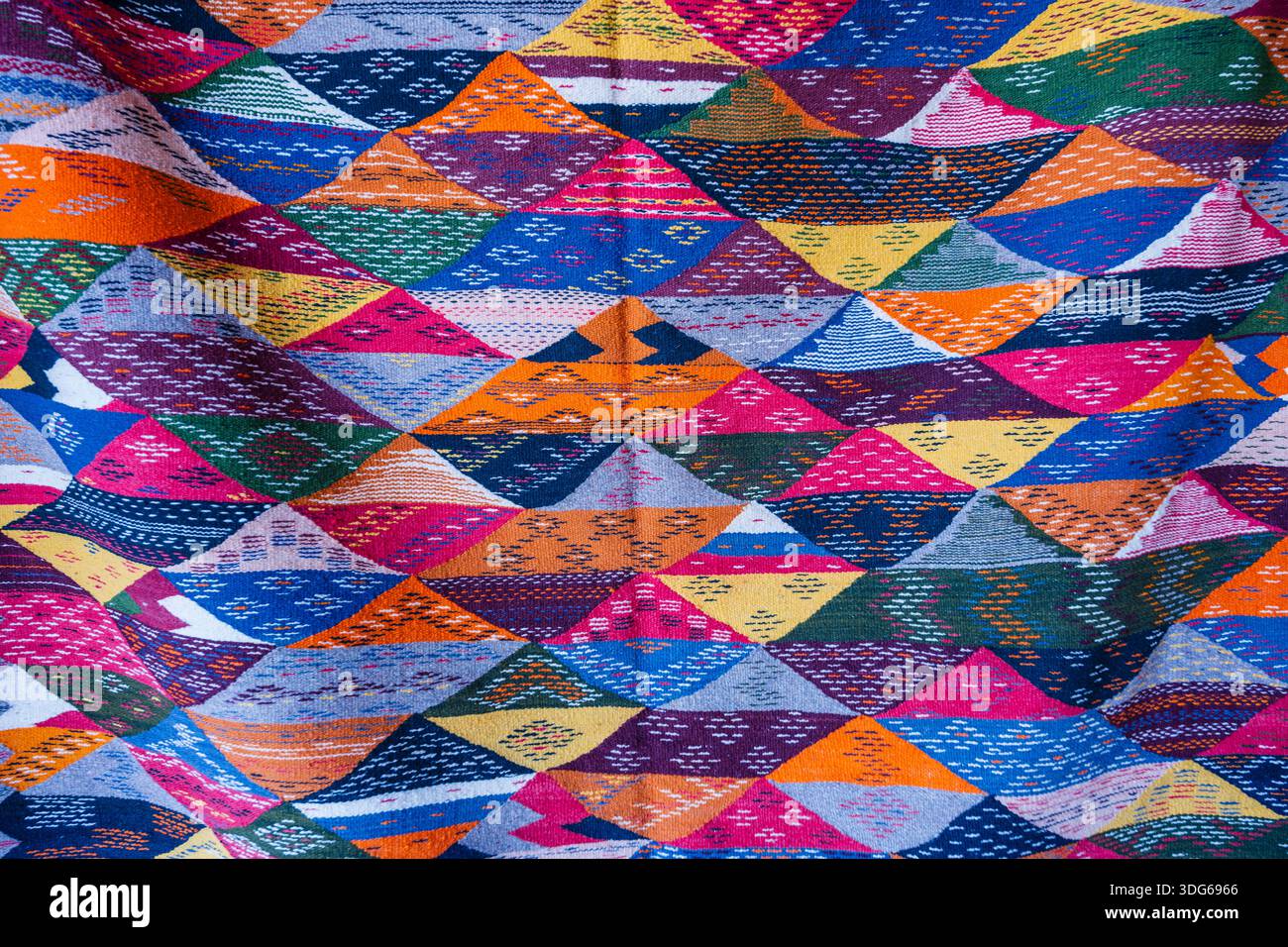 Lebendiges geometrisches Muster mit bunten Dreiecken auf gewebter Oberfläche. Ouarzazate, Marokko Stockfoto