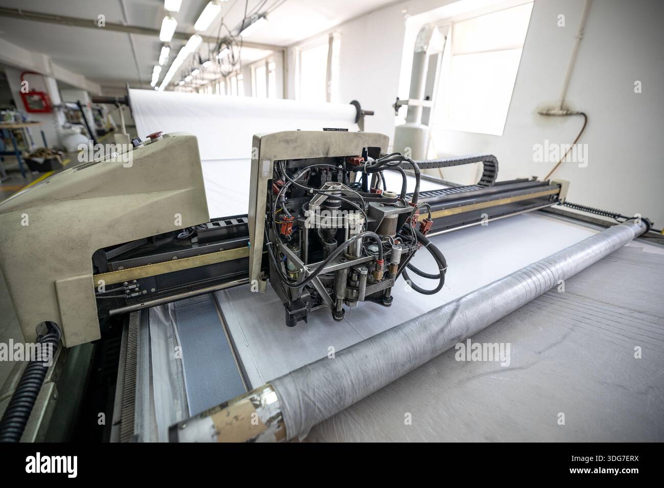 Industrielle Bekleidungsfabrik mit CNC-Gewebeschneidemaschine. High-Tech automatisierte Technologie für hochpräzise Textilverarbeitung und Massenproduktion o Stockfoto