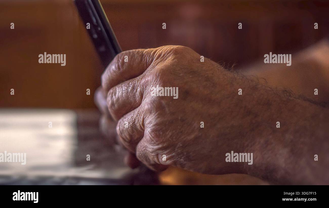 Nahaufnahme älterer Hände, die das Smartphone für Videoanrufe bei warmem Sonnenlicht halten. Leitende Person, die die mobile App auf dem Smartphone nutzt, Stockfoto