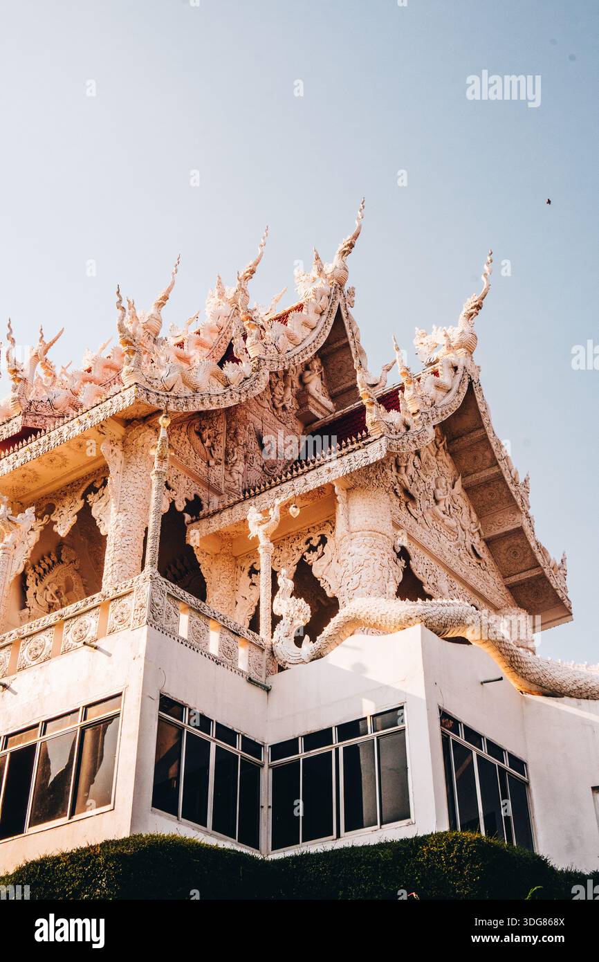 Wat Huay Pla Kang Tempel in Chiang Rai. Februar 2025. Flacher Blick auf eine kunstvoll verzierte weiße Tempeldachecke mit komplizierten Schnitzereien, klarer blauer Himmel/ Stockfoto