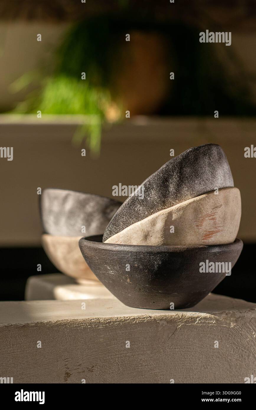 Eine minimalistische Komposition aus handwerklichen Schalen aus Steingut, die auf einem Steinvorsprung angeordnet sind, mit rustikalen Texturen und organischen Glasuren in Anthrazit-Schwarz. Stockfoto