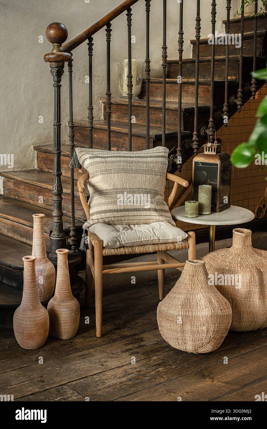 Ein wunderschön gestyltes rustikales Interieur mit einem gewebten Holzsessel und einem gestreiften Kissen. Stockfoto