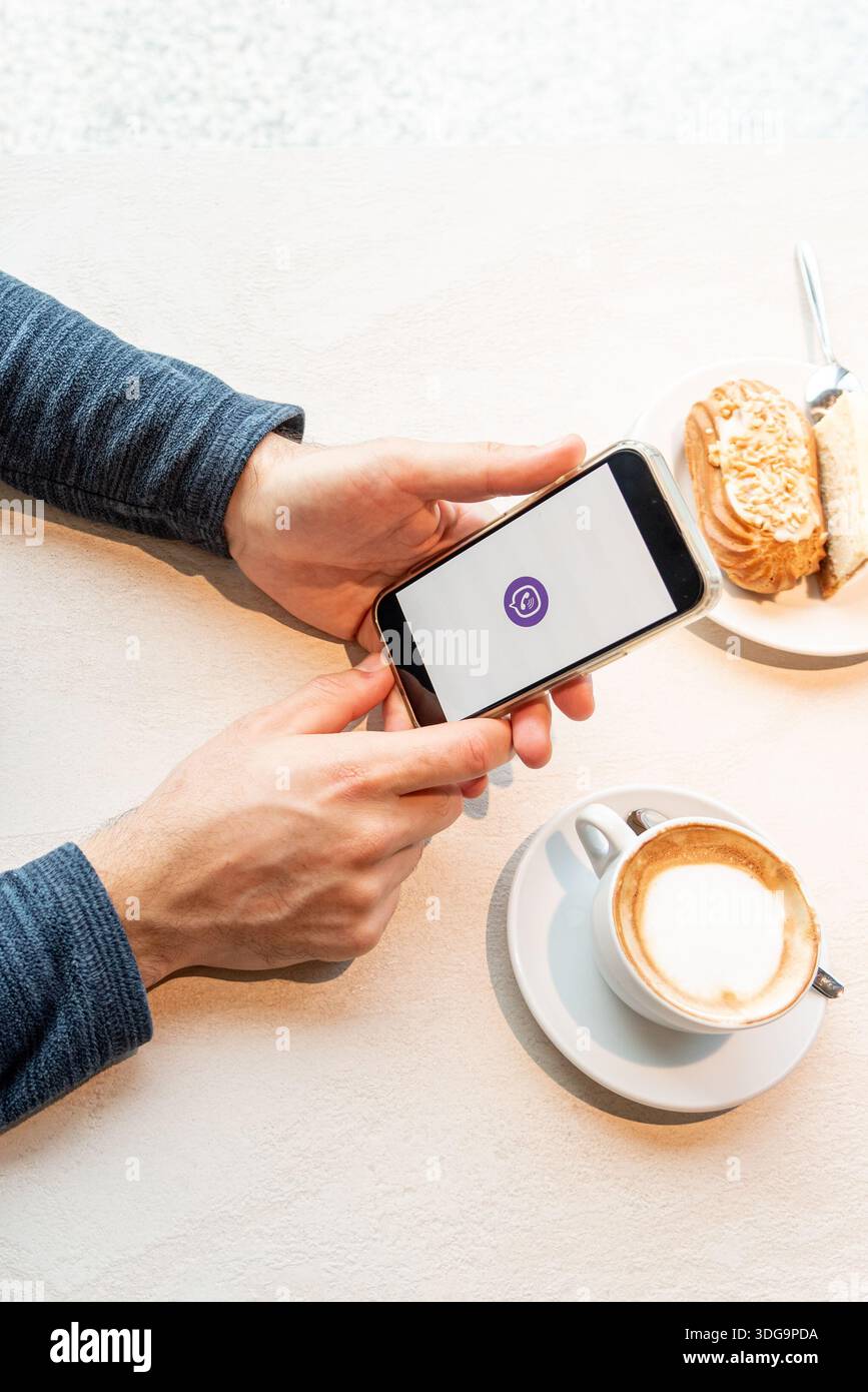 Bar, Montenegro, 9. Januar 2026, Mann ruft oder schreibt Nachrichten über den modernen Viber Mobile Messenger, während er im Café sitzt Stockfoto