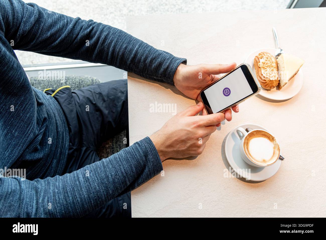 Bar, Montenegro, 9. Januar 2026, Mann ruft oder schreibt Nachrichten über den modernen Viber Mobile Messenger, während er im Café sitzt Stockfoto