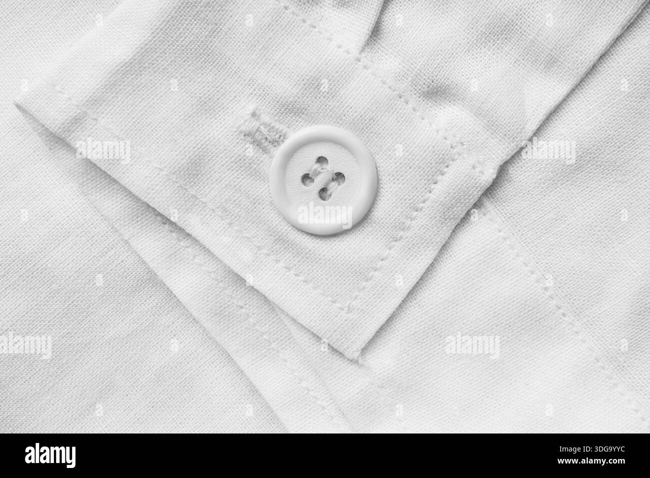 Weißer Hemdknopf auf weißem Baumwollbündchen als Hintergrund aufgenäht Stockfoto