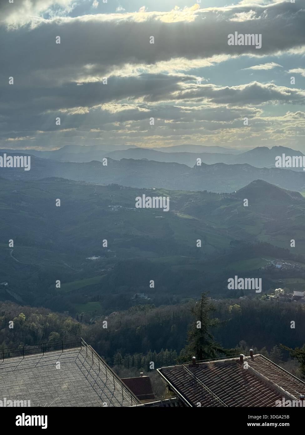 Geschichtete Hügel und nebelige Berge unter einem leuchtenden Himmel in der Landschaft von San Marino Stockfoto