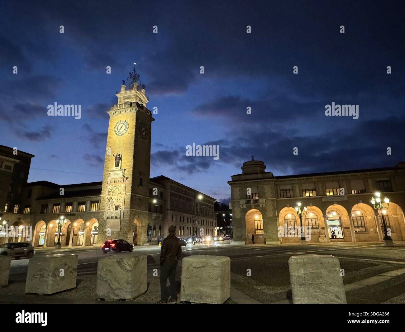 Der Uhrenturm und die historischen Gebäude, die bei Nacht in Bergamo, Italien, unter dramatischem Abendhimmel beleuchtet werden - Smartphone-aufgenommenes Stockfoto