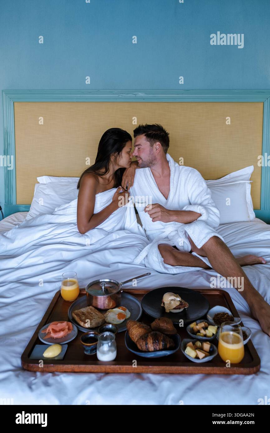 Genießen Sie einen herrlichen Morgen mit einem geliebten Menschen in einem wunderschönen Hotelzimmer in Kapstadt. Ein paar Männer und Frauen haben im Bett gefrühstückt Stockfoto