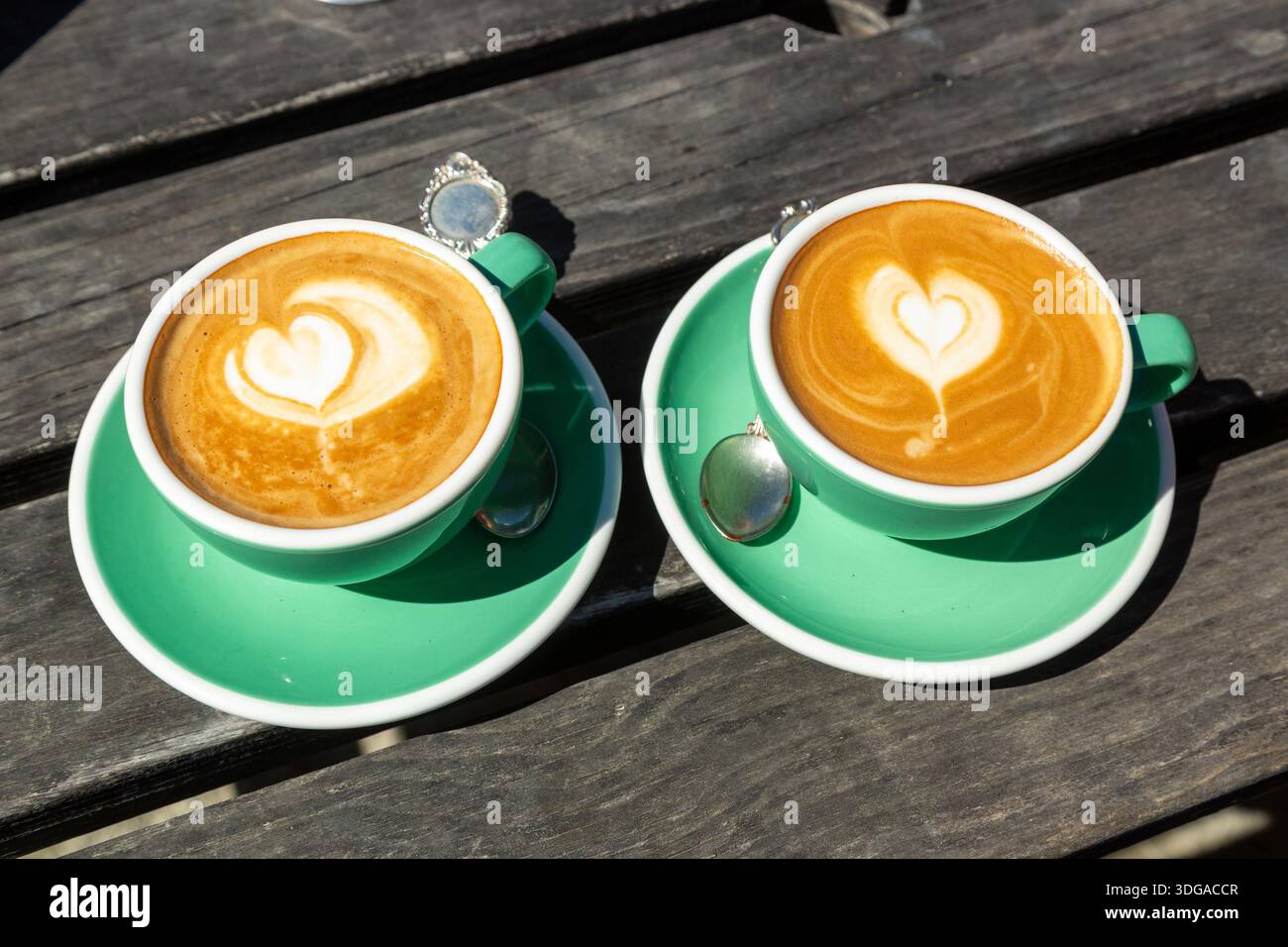 Eine Tasse Kaffee mit herzförmiger Latte Art, serviert in grüner Keramikschale und Untertasse Stockfoto