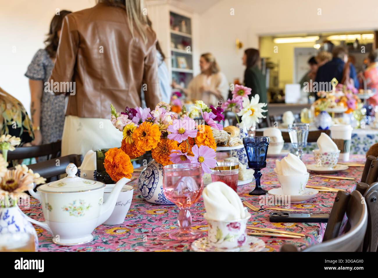 Brunch-Tisch mit Blumen, farbenfrohem Geschirr und Tee mit Blumenmuster Stockfoto