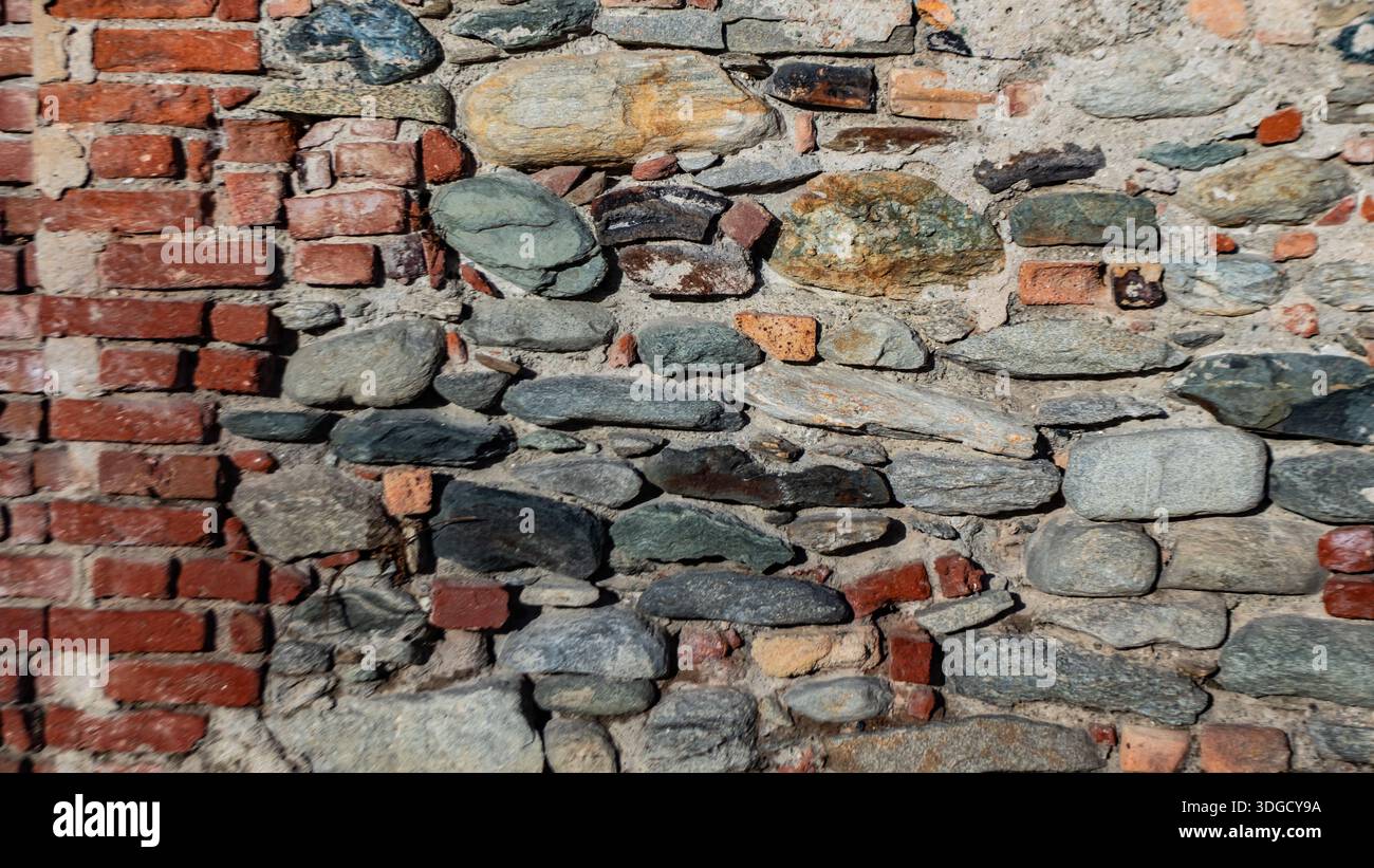 Alte Ziegelstein- und Steinmauer mit mehrschichtigen Texturen und verwitterten Oberflächen, perfekt als architektonischer Hintergrund für Design, Restaurationskonzepte und ur Stockfoto