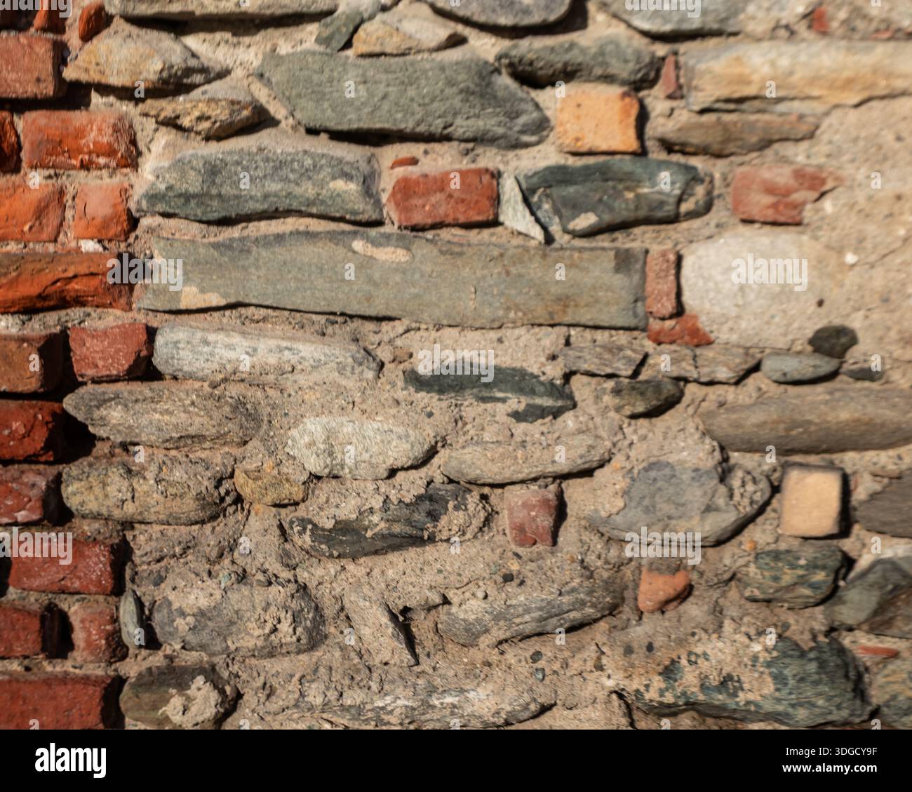 Alte Ziegelstein- und Steinmauer mit mehrschichtigen Texturen und verwitterten Oberflächen, perfekt als architektonischer Hintergrund für Design, Restaurationskonzepte und ur Stockfoto