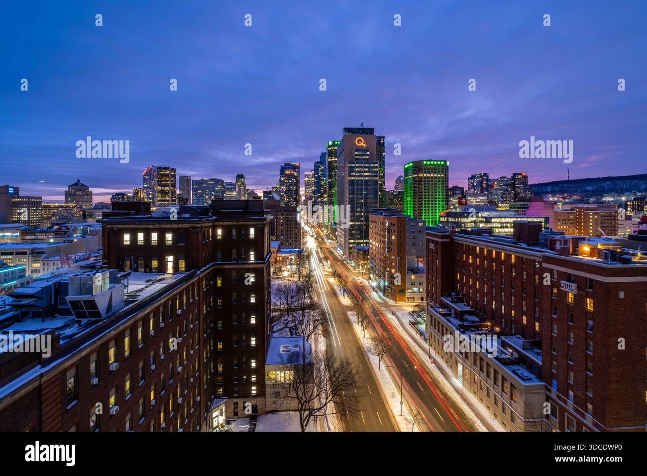 Montreal, QC - 2. Januar 2026: Eine farbenfrohe Langzeitbelichtung der Skyline von Montreal in der Abenddämmerung mit beleuchteten Wolkenkratzern und Autolichtern in Zeitlupe Stockfoto