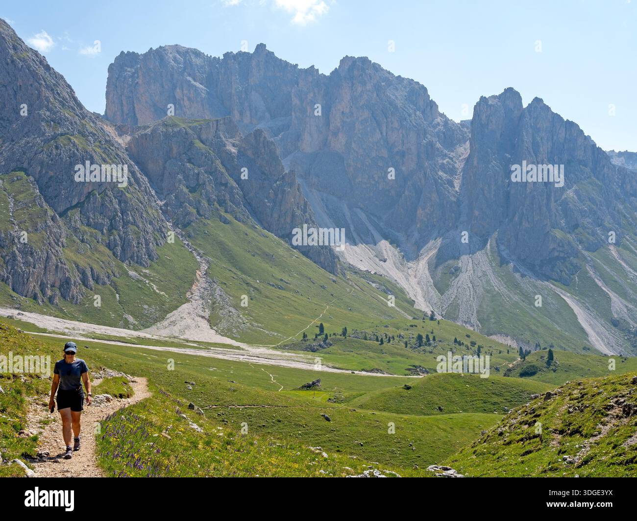 Eine Frau wandert im Puez-Geisler Naturpark unter den Geisellern Stockfoto