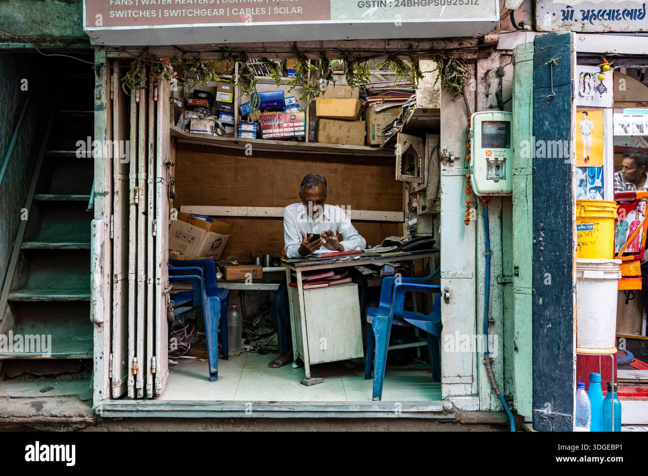 Ladenbesitzer, der das Handy beobachtet, in der Altstadt von Ahmedabad, Gujarat, Indien, Südasien, Asien Stockfoto
