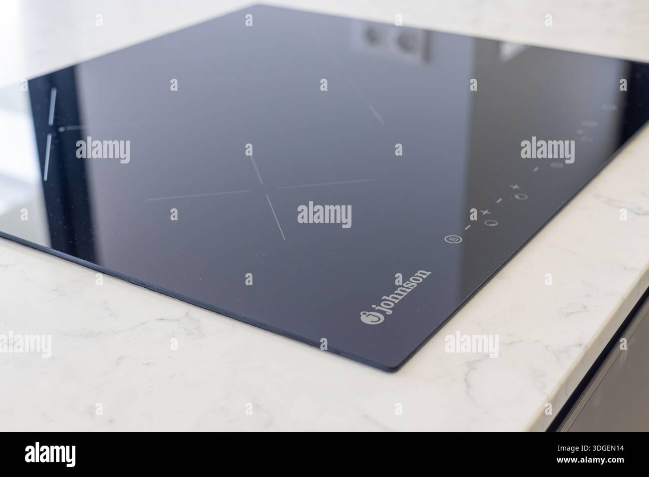 Elegantes Johnson Induktionskochfeld mit Touch-Bedienelementen, eingebettet in weiße Marmorarbeitsfläche Stockfoto