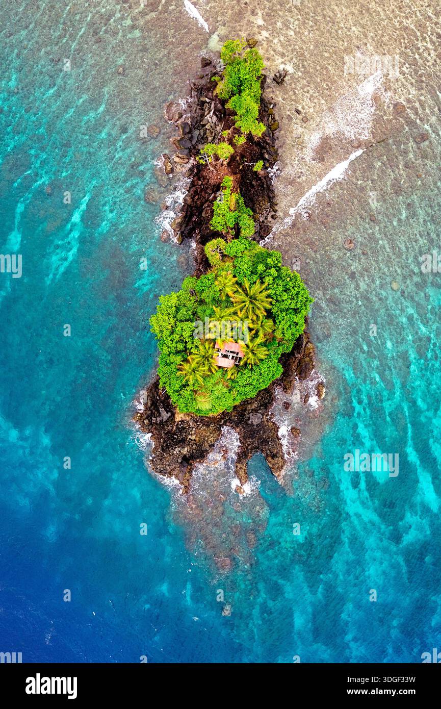 Spektakuläre tropische Insel Tagulandang nördlich von Sulawesi in Indonesien, aus der Vogelperspektive auf eine kleine felsige Insel mit kleinem Haus und Palmen Stockfoto