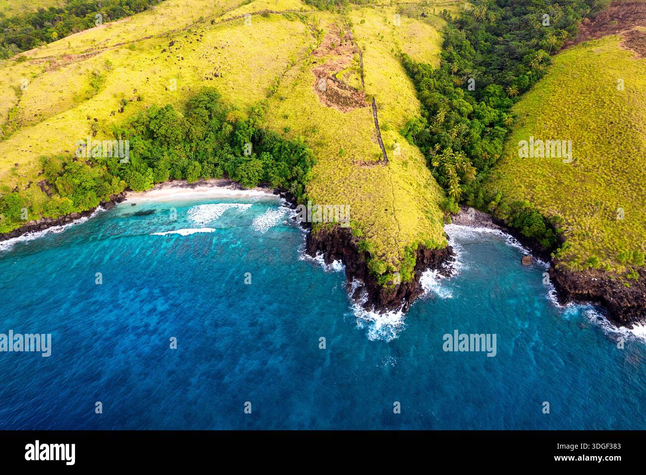 Spektakuläre tropische Insel Tagulandang nördlich von Sulawesi in Indonesien, grasbewachsene Hügel und Klippen umgeben von weißen Sandstränden Stockfoto
