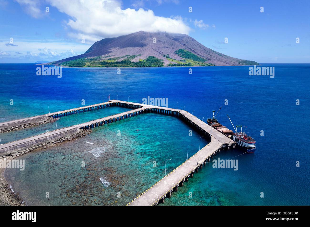 Kleiner Hafen auf Tagulandang Insel mit ruang Insel im Hintergrund, ruang, aktiver Vulkan, wunderschöne Korallenriffe, Schiff am Dock Stockfoto