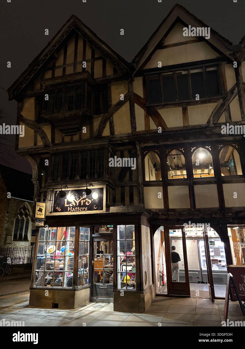 Historisches Fachwerkgebäude im Tudor-Stil mit nächtlicher Beleuchtung in einer ruhigen englischen Stadtstraße. - Smartphone-aufgenommenes Stockfoto