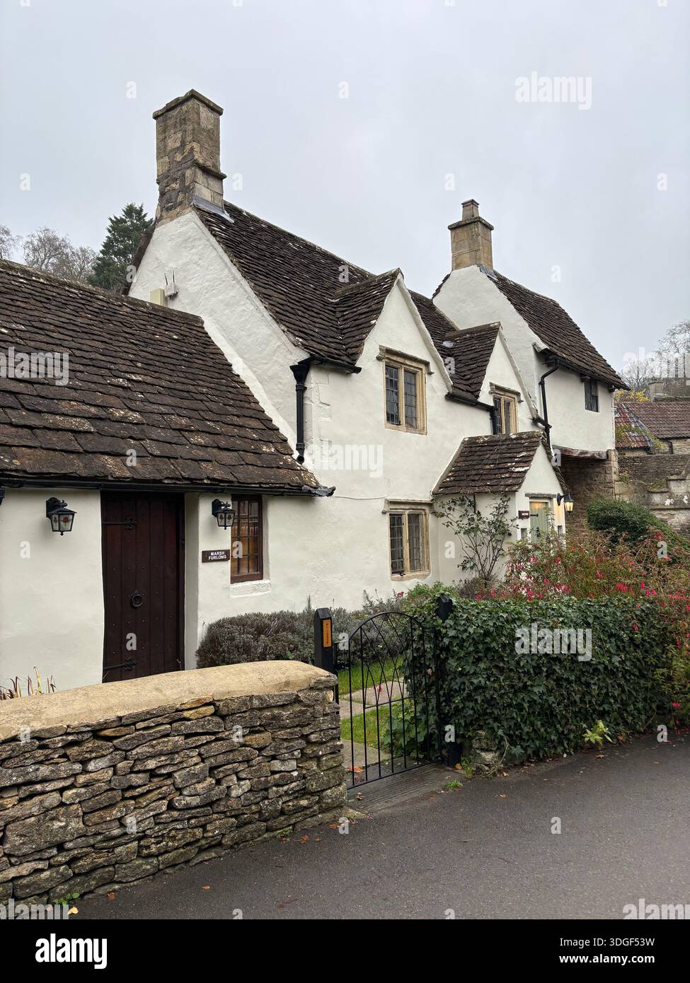 Traditionelle weiß getünchte Cotswold Cottages mit Steindächern und Schornsteinen entlang einer ruhigen Dorfstraße in England. Stockfoto
