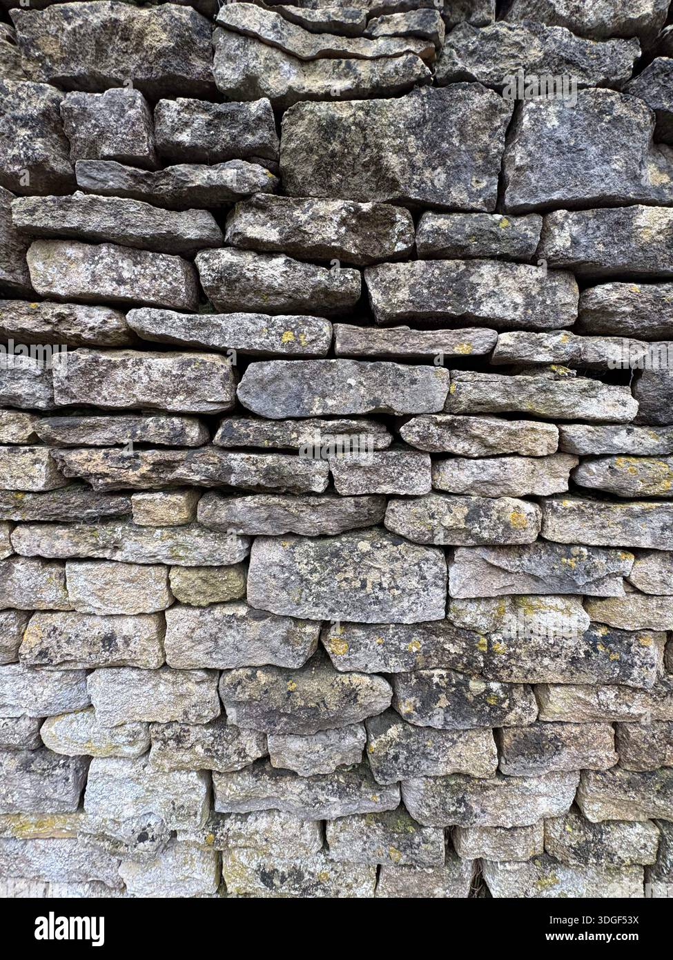 Nahaufnahme der traditionellen Trockensteinmauer aus verwitterten Kalksteinblöcken, die eine natürliche rustikale Steinstruktur bilden. - Smartphone-aufgenommenes Stockfoto