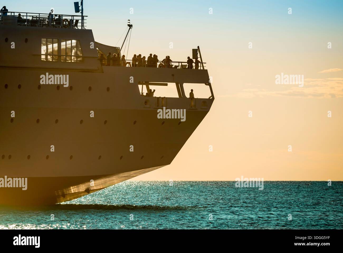 Kreuzfahrtschiff, im Sommer beobachten Menschen einen Sonnenuntergang, während sie an Deck im Heck eines großen Kreuzfahrtschiffs im Mittelmeer stehen. Stockfoto