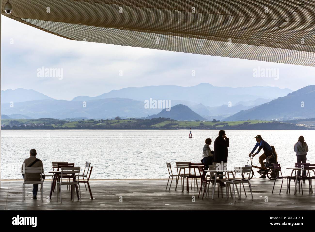 Santander, Spanien – 20. November 2021: Ein Radfahrer hält an, um sich mit Menschen im Außenbereich unter der Architektur des Centro Botin bei einem Bergwettkampf zu unterhalten Stockfoto