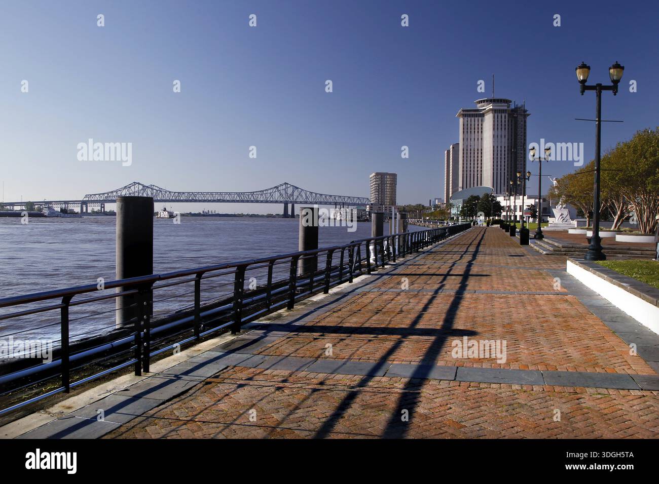 Promenade mit Hochhaus am Flussufer unter klarem Himmel, New Orleans, Louisiana, USA Stockfoto