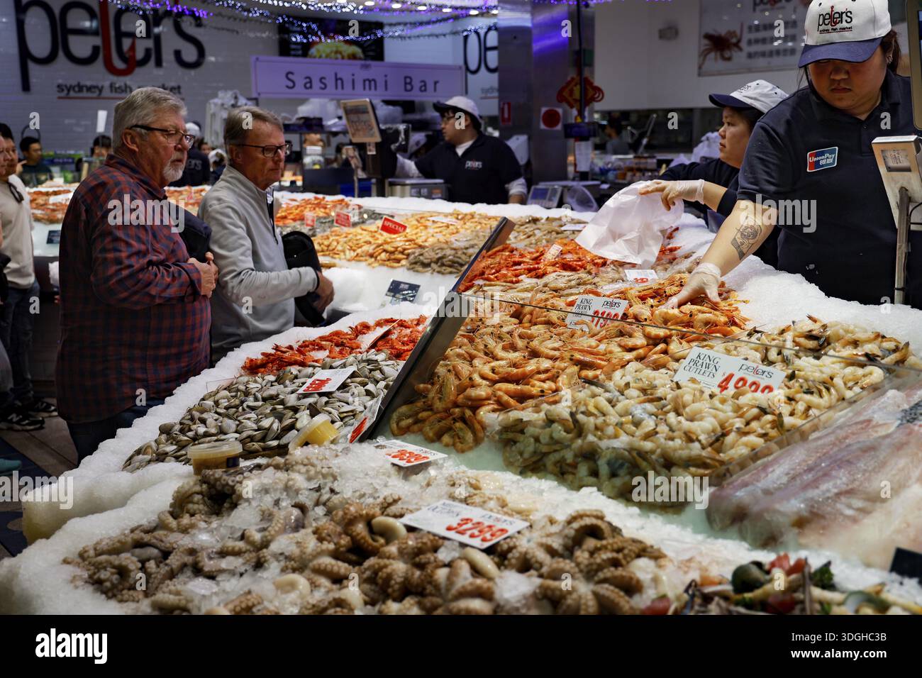 Die Kunden sehen sich die vielfältige Auswahl an Meeresfrüchten an einem geschäftigen Verkaufsstand in Sydney, Australien, an Stockfoto