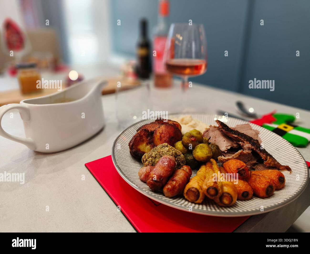 Gänsenbraten, Weihnachtsessen mit Karotten, Pastinaken, Rosenkohl und Schweinen in Decken, mit Soße und Wein - Smartphone-aufgenommenes Stockfoto