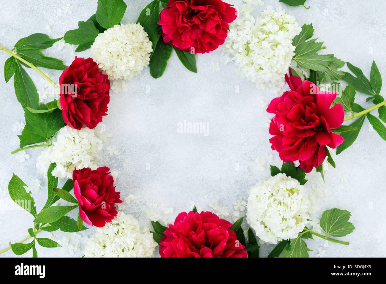 Blumenkranz mit roten und weißen Blumen auf hellem Hintergrund, runder Rahmen mit Kopierraum Stockfoto